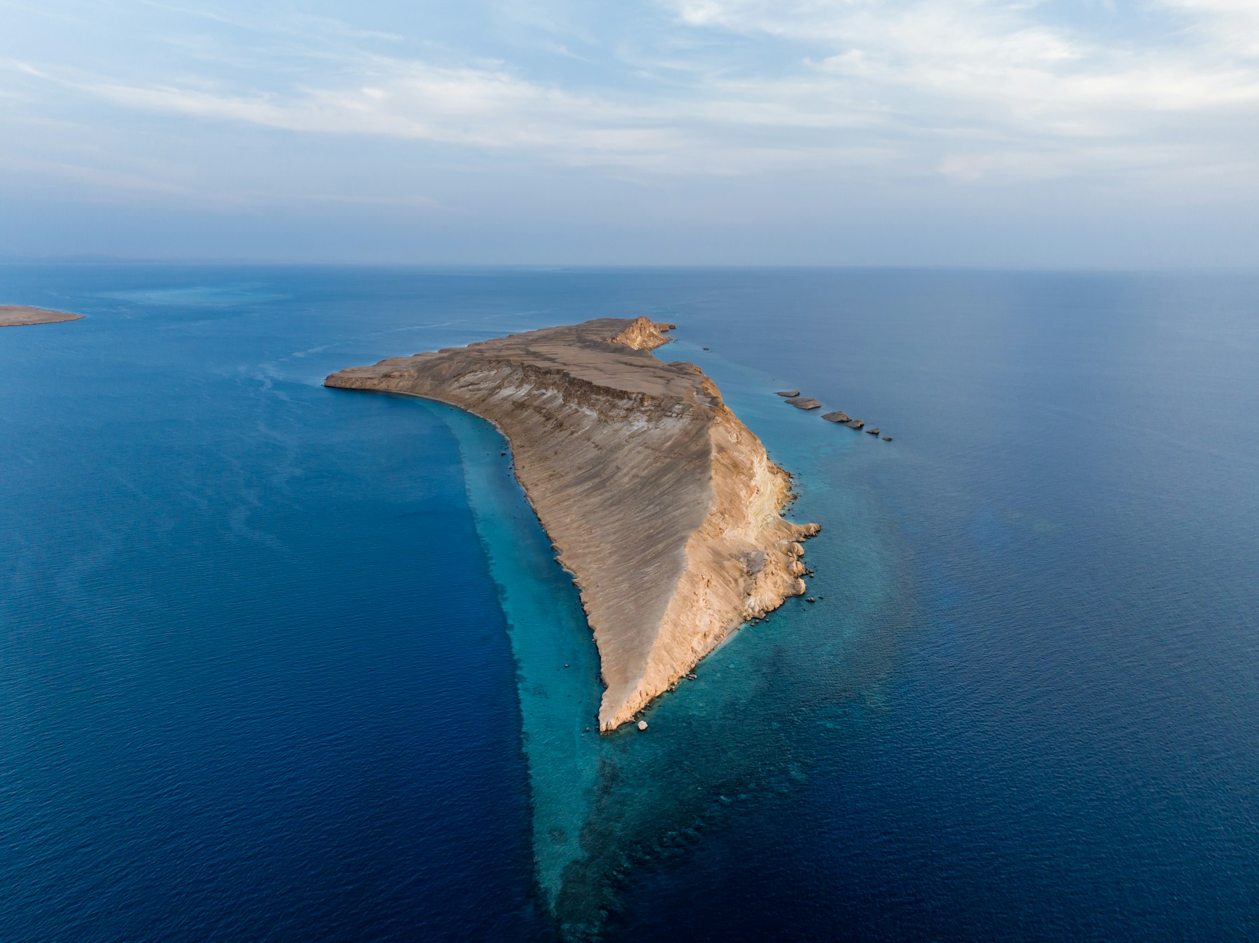 Red desert cliffs meeting the sea in Saudi Arabia.
