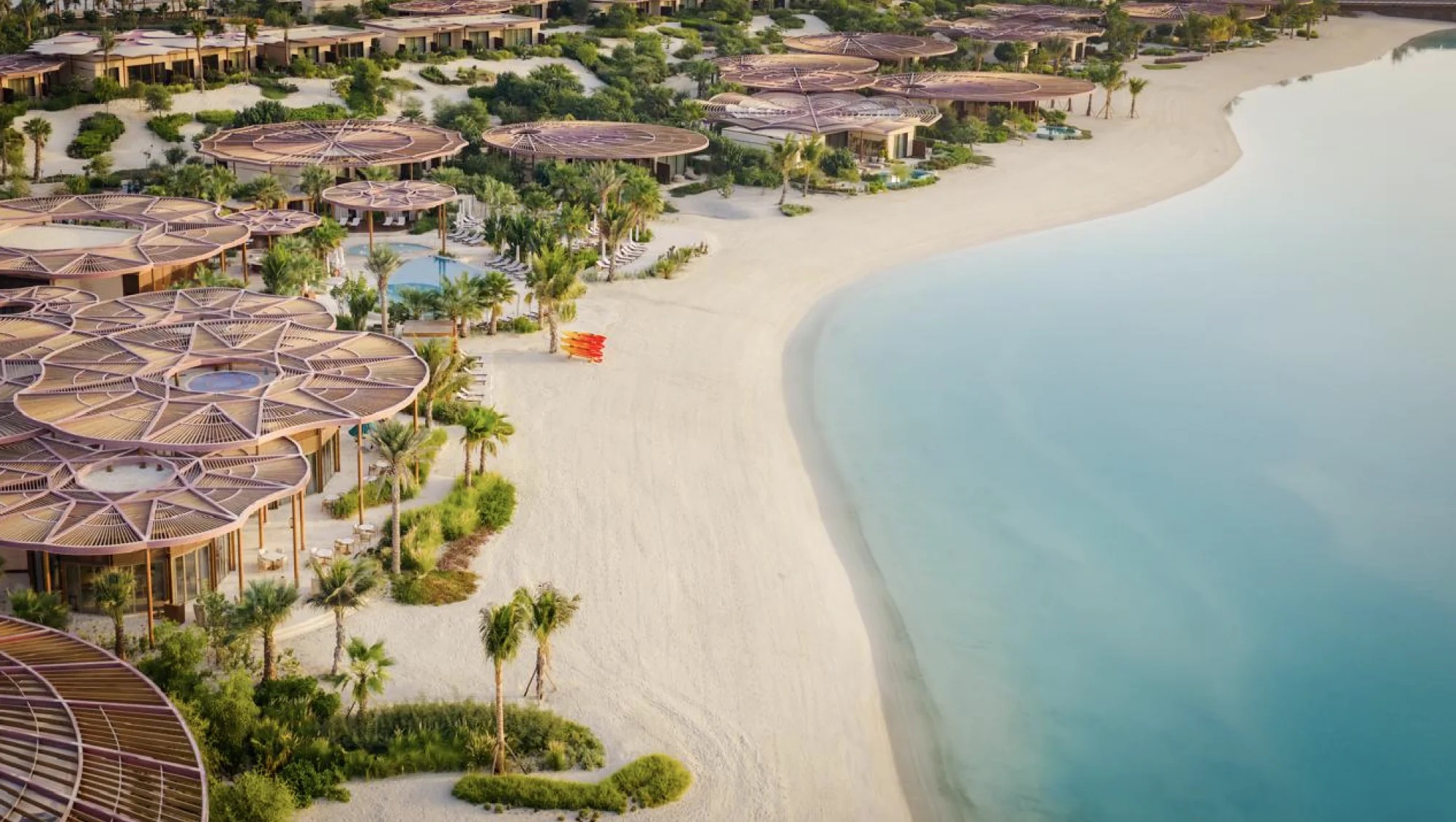 Raffles The Red Sea's curved beachfront buildings, palms and pale sand beside the lagoon on Shura Island.