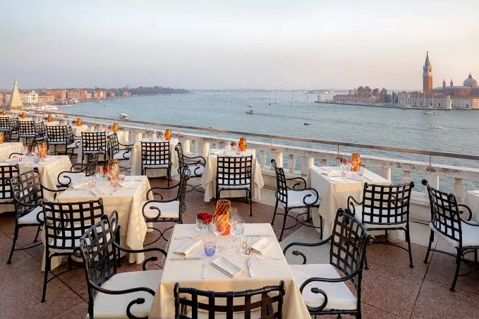 Terrazza Danieli laid for dinner at dusk, looking across the water to San Giorgio Maggiore.