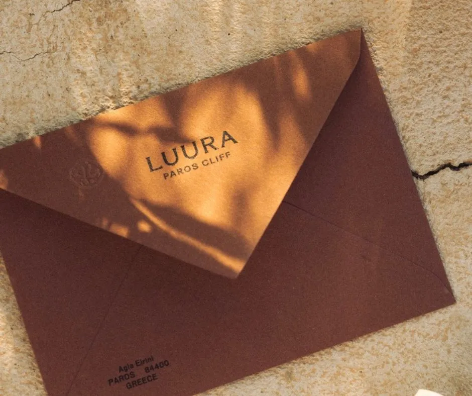 A Luura Paros Cliff envelope on a sunlit stone wall.