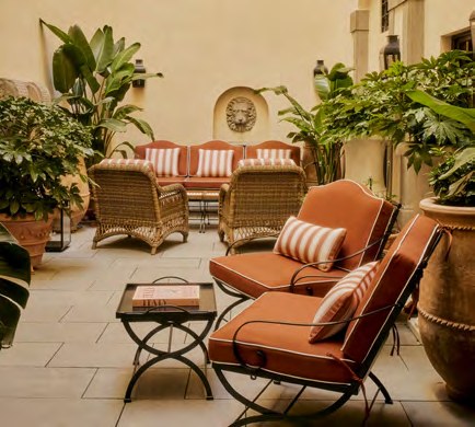 The shaded patio at La Réserve Firenze, with rattan chairs, potted plants and a stone fountain.