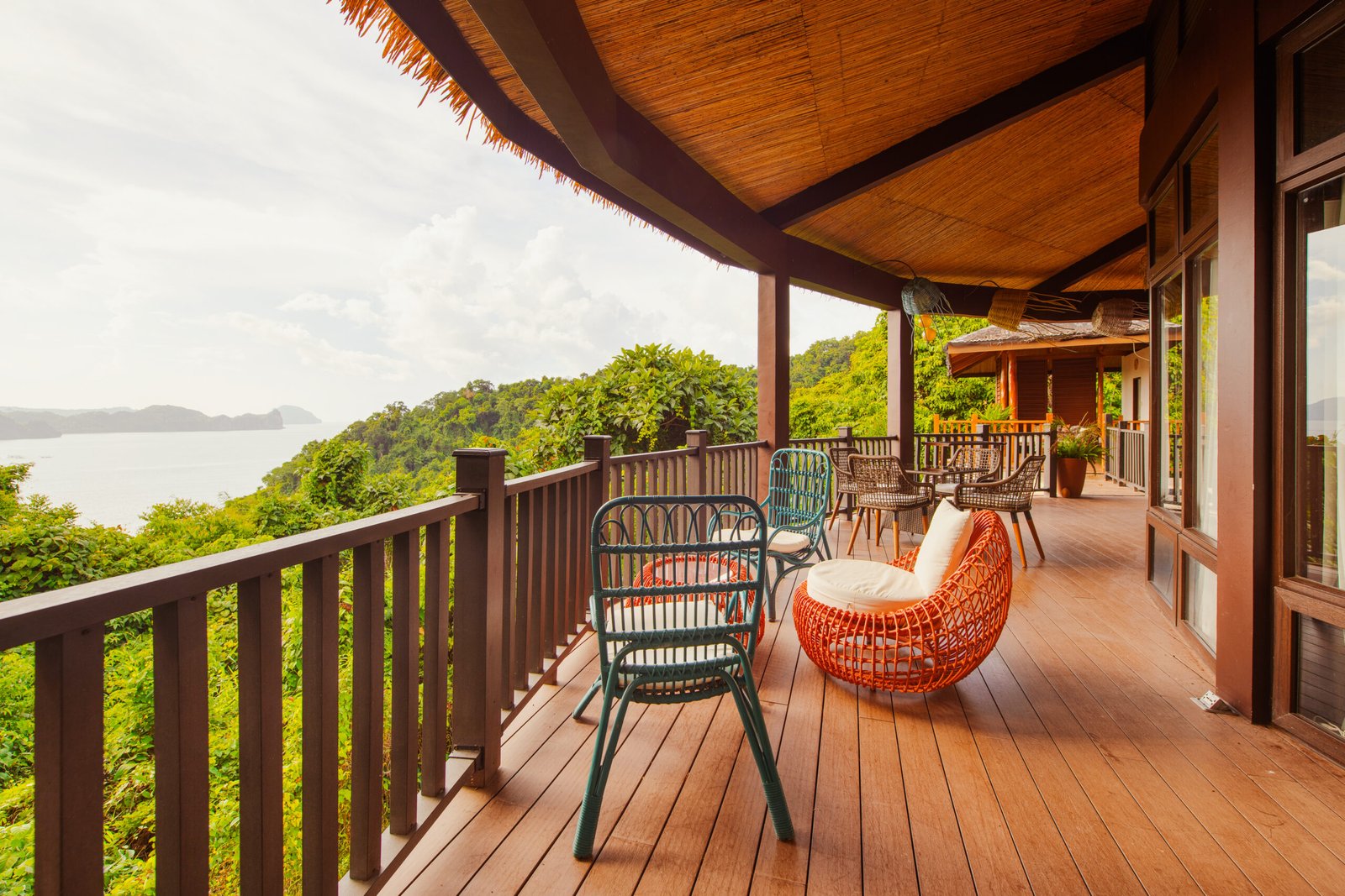 A wooden villa terrace with rattan chairs and sea views at Lihim Resorts, El Nido